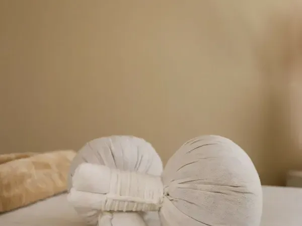 Deux tampons de tissu écru garnis de plantes, posés sur le linge de soin